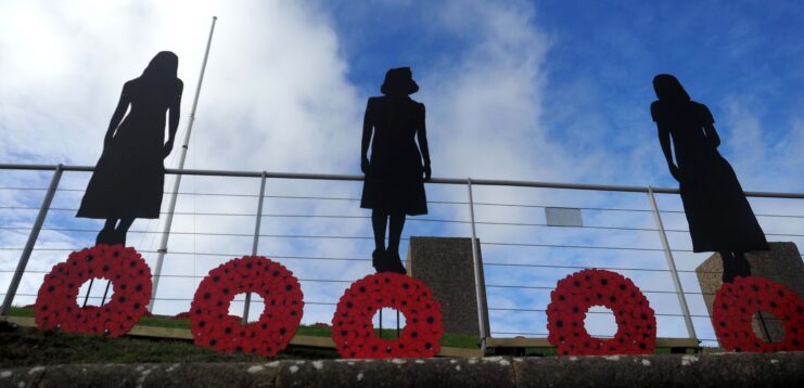 Three figures that make up a Standing with Giants display. Wreaths made of poppies are positioned at their feet