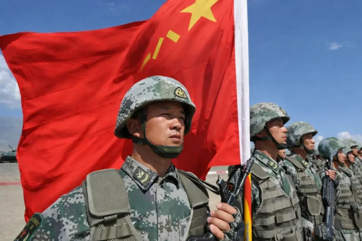 Image of the Chinese army standing next to a Chinese flag.