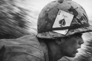 An American soldier in Vietnam with an Ace of Spades card attached to his M1 helmet.