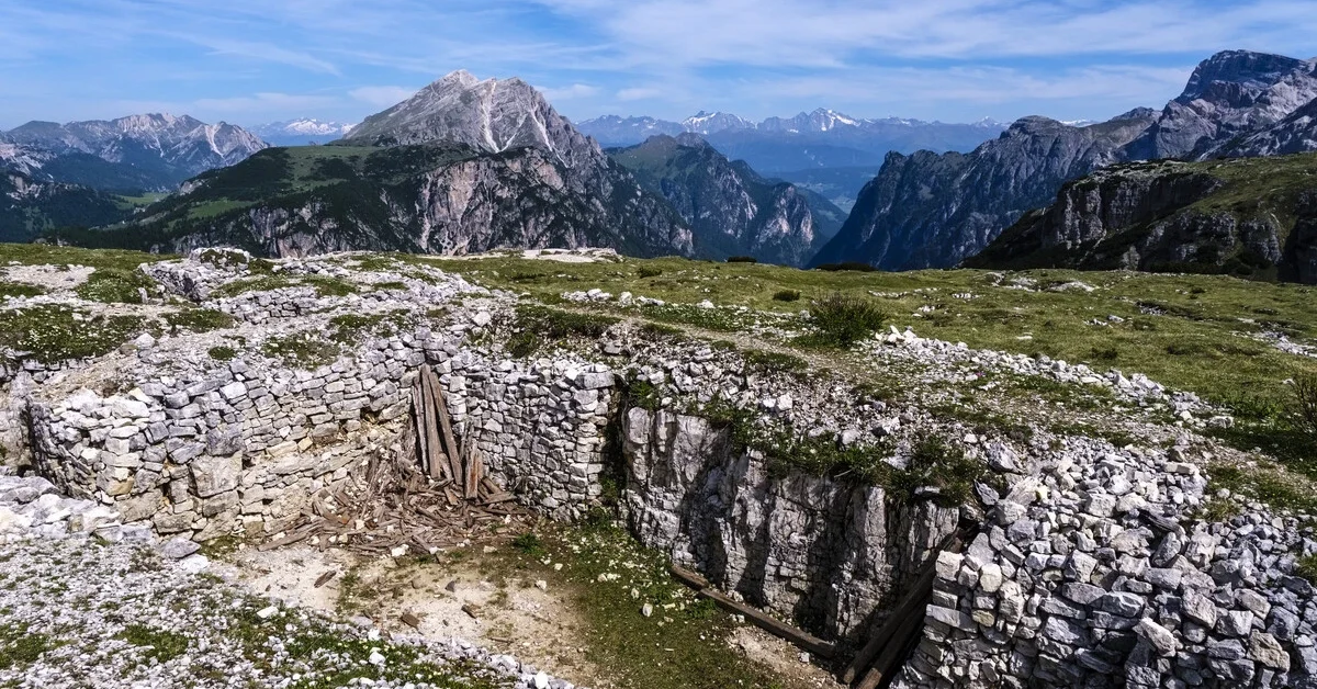 2025/06/18: Ruined World War I trenches on Monte Piana with Dolomite peaks in the distance under a blue sky.The entire Dolomites are part of the Unesco World Heritage. 