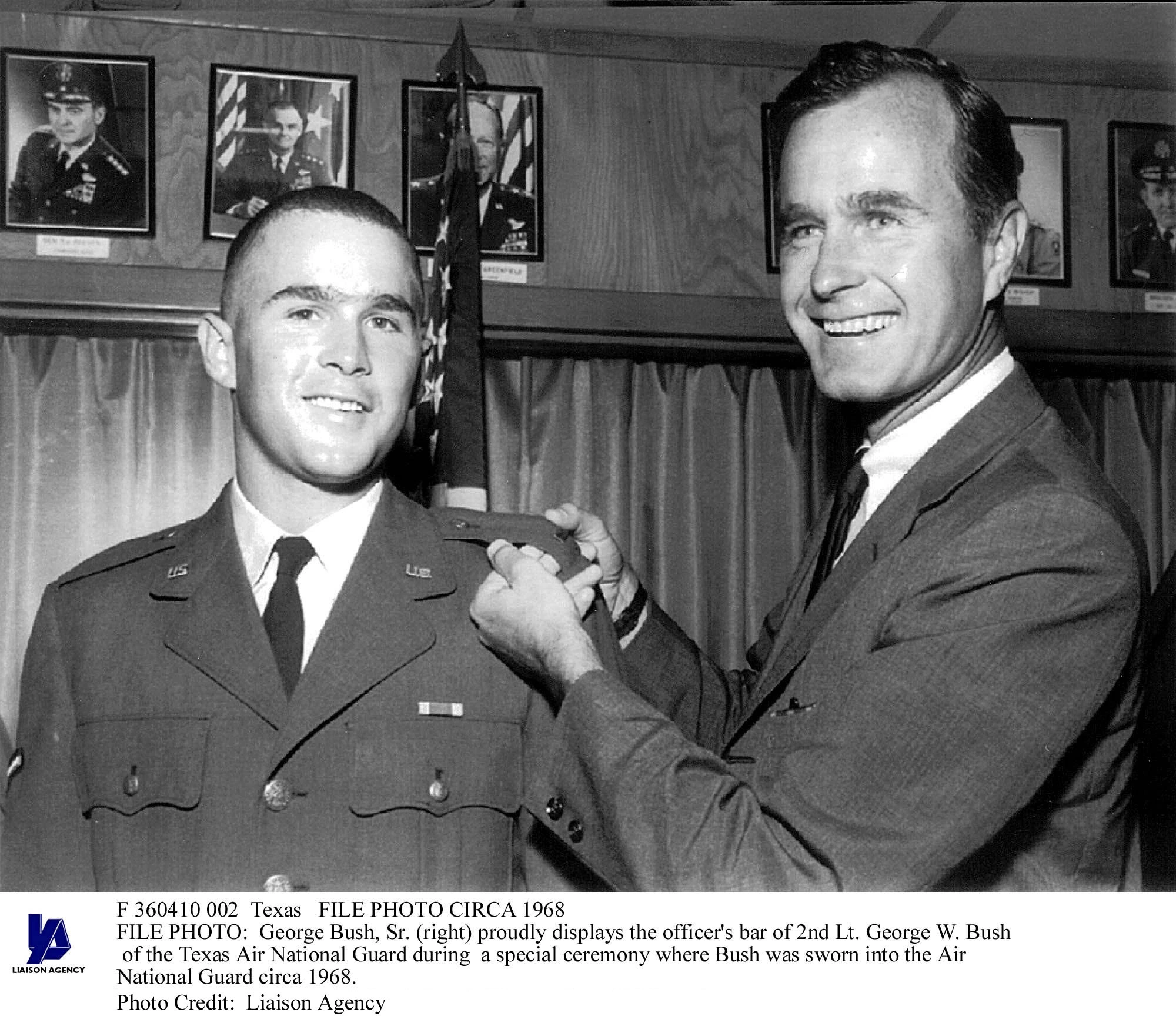 George Bush, Sr. (right) proudly displays the officer's bar of 2nd Lt. George W. Bush from the Texas Air National Guard during the ceremony in which the younger Bush was sworn into the Air National Guard, circa 1968