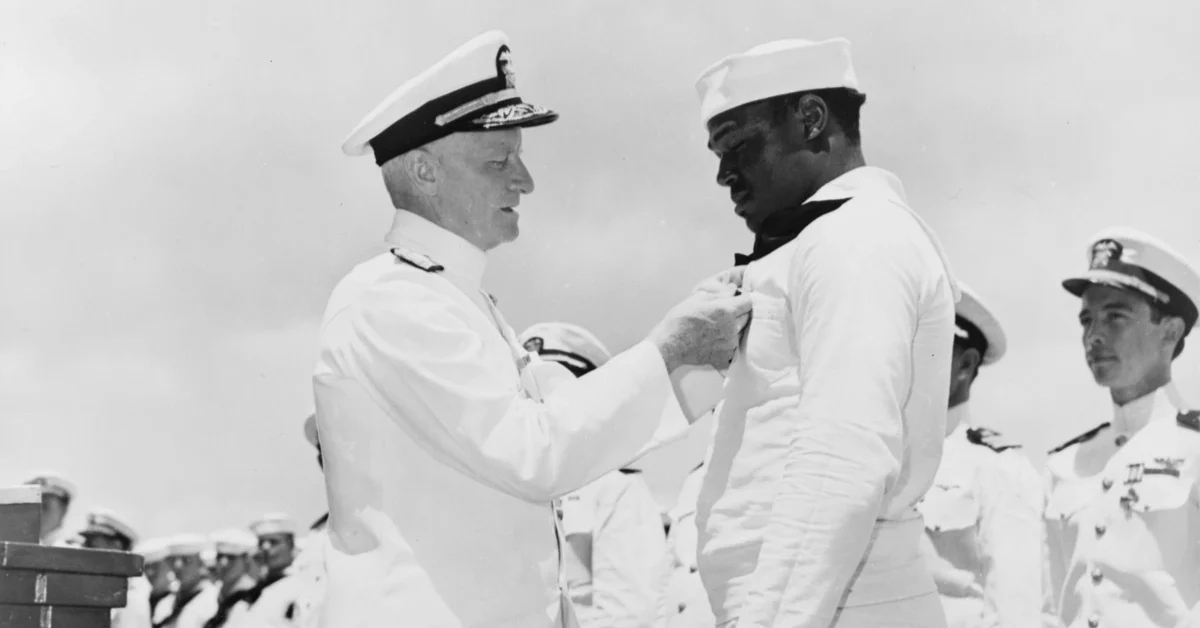 Admiral Chester W. Nimitz, USN, Commander-in-Chief, Pacific Fleet, pins the Navy Cross on Doris Miller, Steward's Mate 1/c, USN, at a ceremony on board a U.S. Navy warship in Pearl Harbor, T.H., May 27, 1942