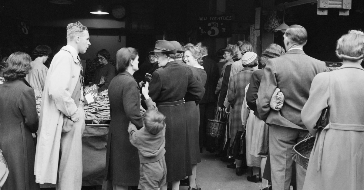 Britain Queues For Food- Rationing and Food Shortages in Wartime, London, England, UK, 1945Men, women and children queue for potatoes outside 'J Wood' the greengrocer at 97-99 High Road, Wood Green, London. The display in the foreground contains broad beans. A sign in the background states that new potatoes cost 3 1/2d per lb.