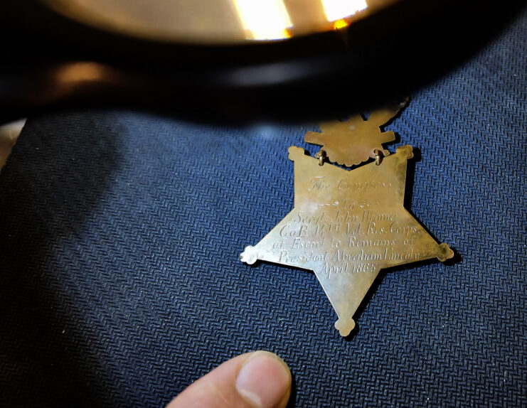 Back view of a Medal of Honor against a dark backdrop, with an inscription on it